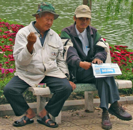 Friends sitting on a bench by Hoan Kiem Lake in Ha Noi, Vietnam