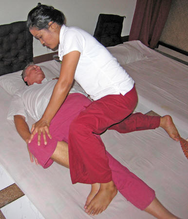 May doing a spinal twist on Billy. Chiang Mai massage, Thailand