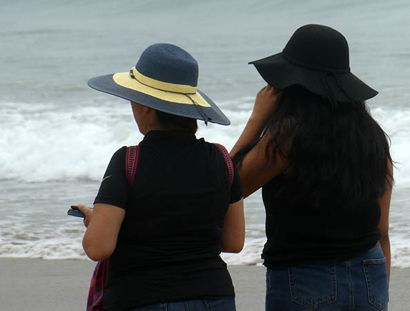 Women on cell phones wearing beach hats, Chacala, Mexico