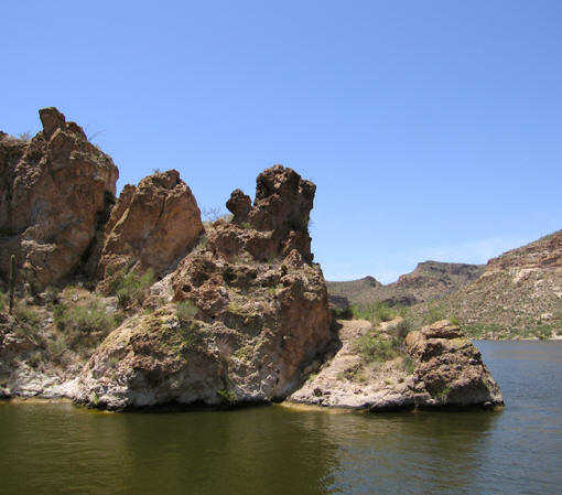 Pocked boulders make a jagged outline against the dazzling blue sky. Canyon Lake, AZ