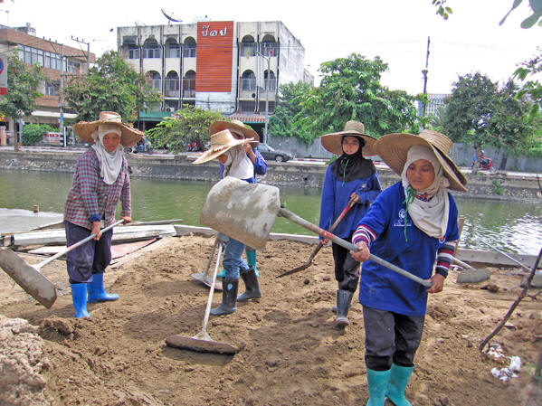 Thai women construction workers, covered head-to-toe flatten the earth. Chiang Mai, Thailand