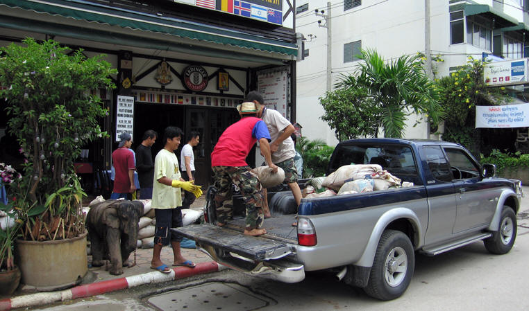 Men heave sandbags out of the back of their truck. Chiang Mai, Thailand