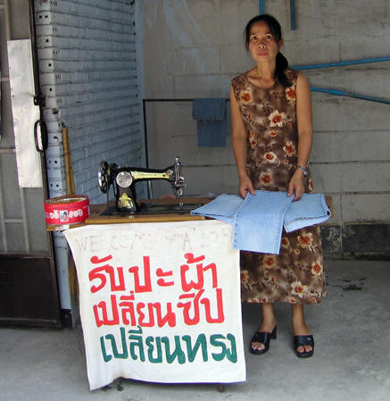 Thai seamstress with sign advertising her business